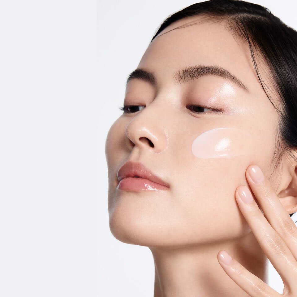 A woman gently applies Sulwhasoo Concentrated Ginseng Rejuvenating Cream to her cheek, showcasing its creamy texture and promising a deeply hydrating and wrinkle-softening experience for radiant, firmer skin.