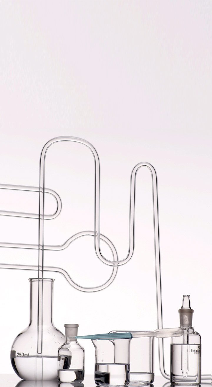 Glass laboratory equipment, including beakers and tubing filled with clear liquids, showcasing the scientific process behind the development of Laneige's Water Sleeping Mask.