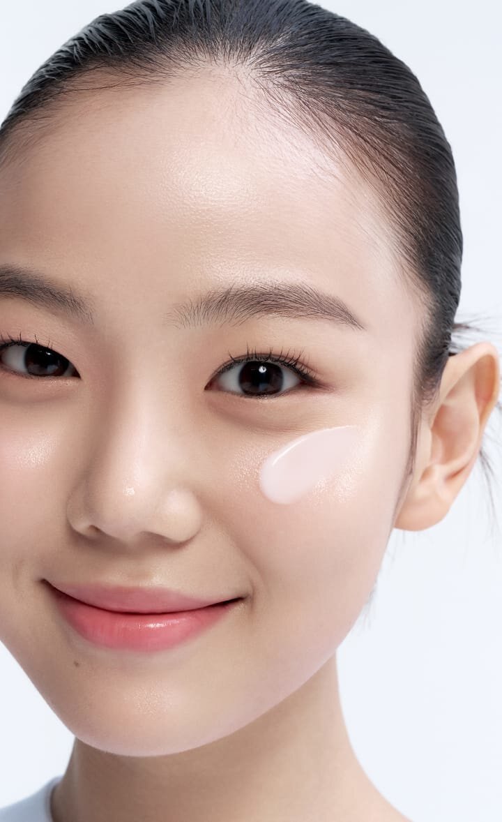 一位女子微笑著，將一小撮LANEIGE 水庫補濕清爽防曬霜 SPF50+ PA++++ 輕抹在臉頰上，展現其輕盈保濕的質地。