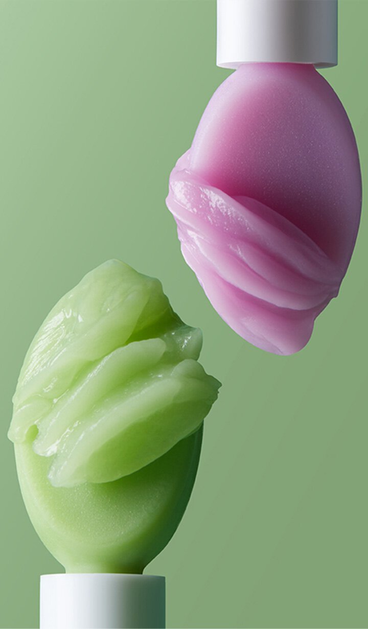 Two applicators with swirled textures of Laneige Lip & Eye Sleeping Mask in green and purple, showing their rich, balm-like consistency.