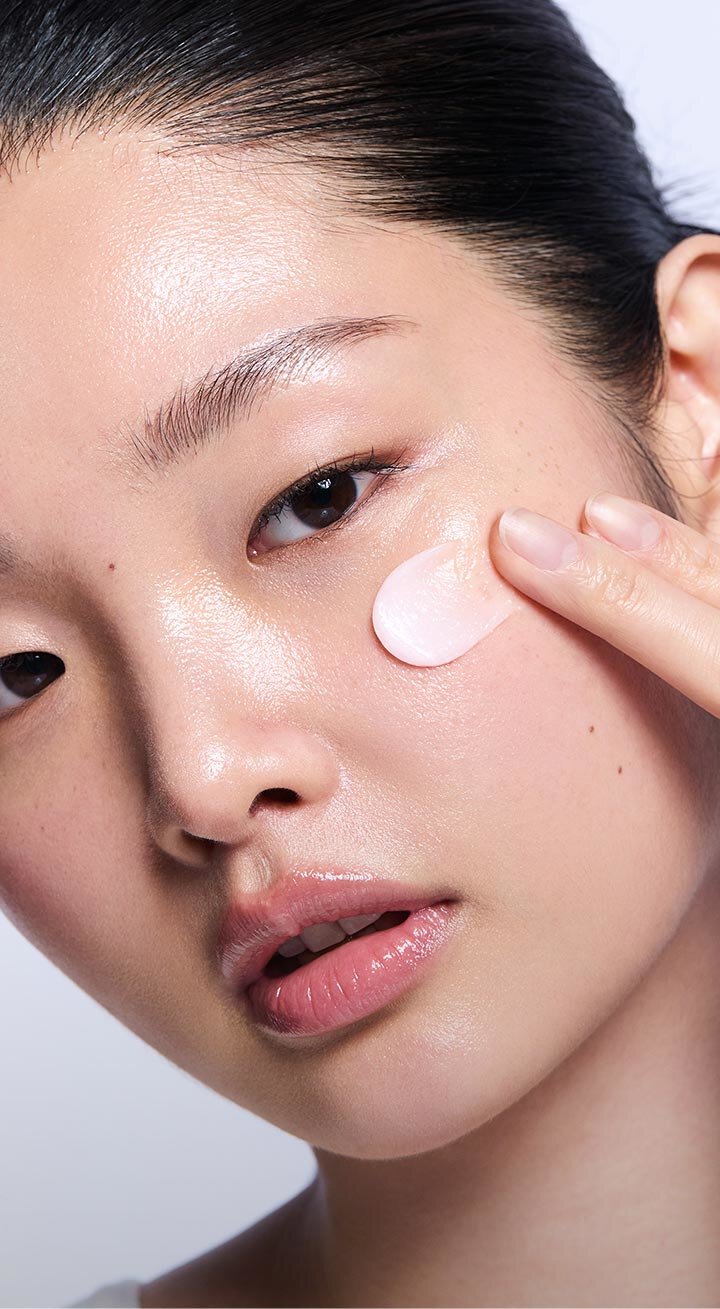 一位女性輕柔地將一坨淡粉色的蘭芝修護睡眠面膜塗抹於臉頰，展現出面膜的乳霜質地及其適用於乾燥敏感肌膚的特性。