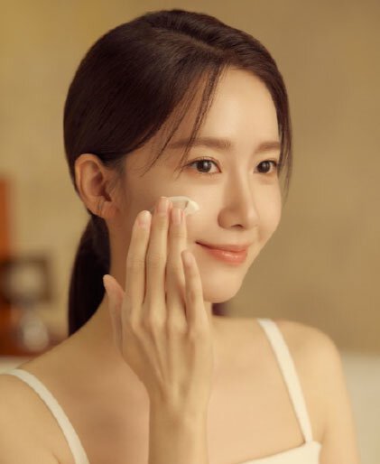 Yoona gently applies a creamy, white moisturizer to her cheek, showcasing the rich texture of Sulwhasoo's Concentrated Ginseng Rejuvenating Cream and its rejuvenating effect on the skin.