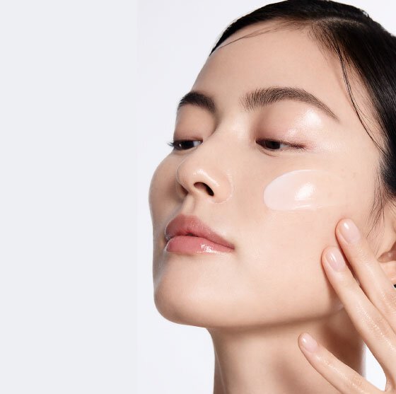 A woman gently applies a dollop of Sulwhasoo Concentrated Ginseng Rejuvenating Cream to her cheek, showcasing the cream's smooth texture and illustrating its moisturizing and wrinkle-softening benefits.