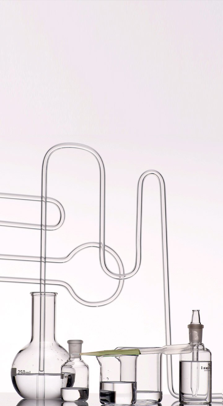 Laboratory glassware, including beakers and tubing, filled with clear liquids, showcasing the scientific process behind the development of Laneige's Cica Sleeping Mask.