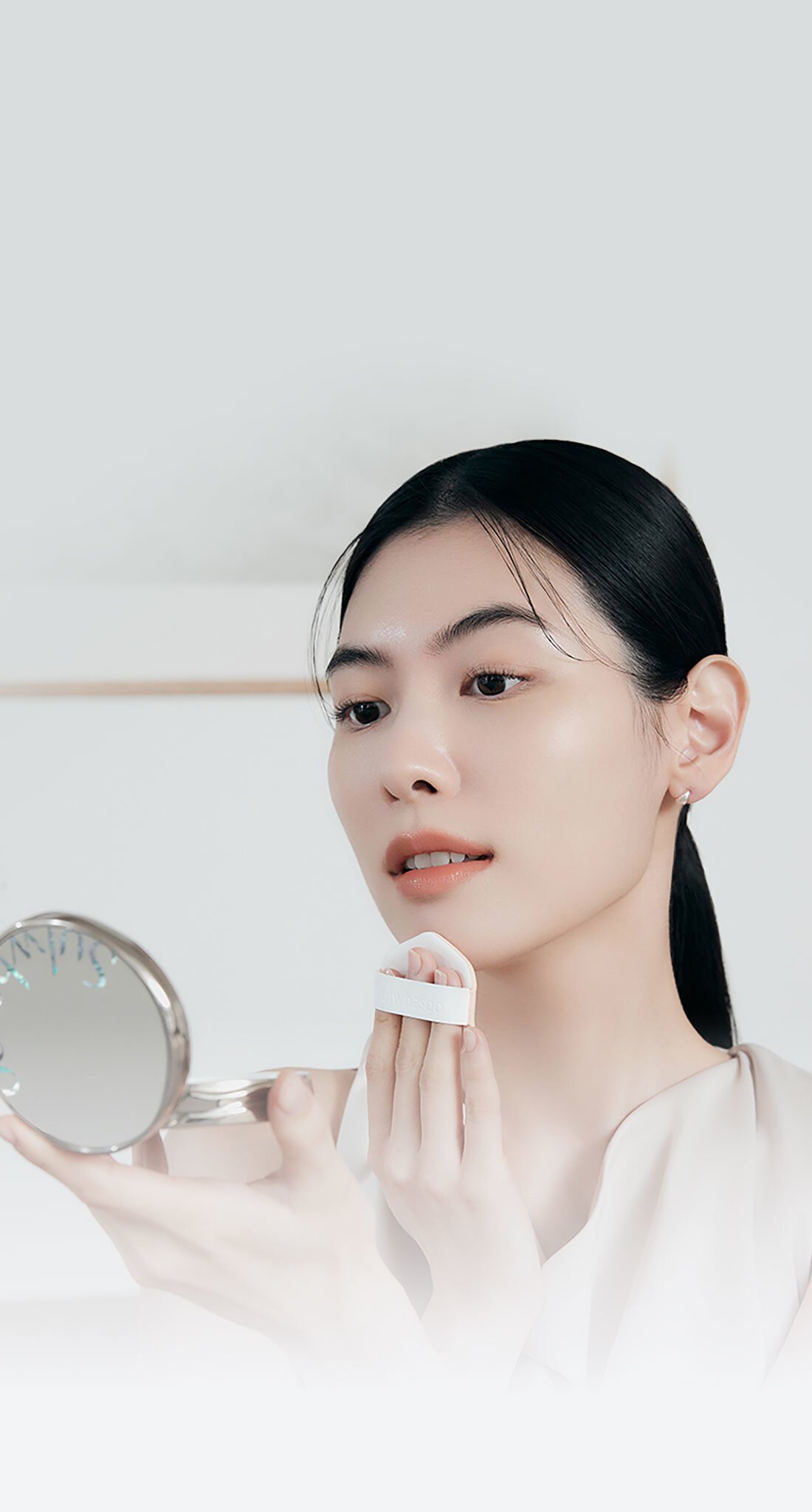 A model is wearing makeup with a Perfecting Cushion