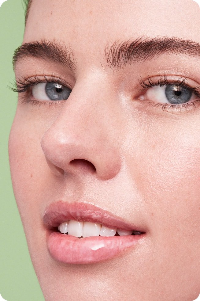 A close-up of a woman with moisturized and glossy lips, showing the radiant color and smooth finish of LANEIGE LIP GLOWY BALM TARO BUBBLE TEA.