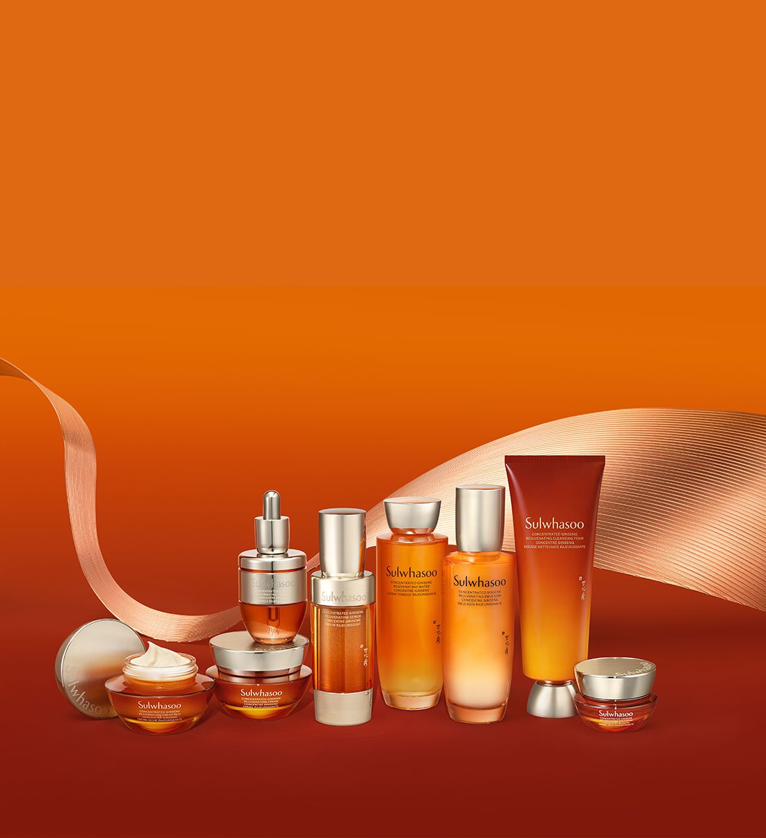 Several Sulwhasoo skincare products, including creams, serums, and cleansers, are artfully arranged against a warm orange background, showcasing the brand's luxurious ginseng-infused line designed for deeply hydrating and rejuvenating skin.

