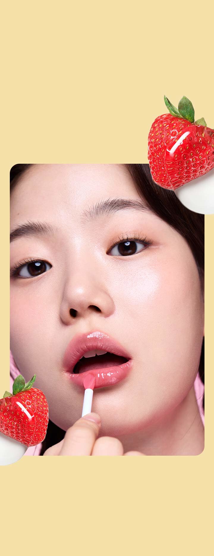 A person applies the Laneige Lip Sleeping Mask in Strawberry Shortcake, its glossy pink texture enhancing their lips, while vibrant strawberries playfully frame the image.