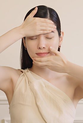 一位女性輕柔地按摩臉部，展示雪花秀高麗人蔘精華活膚霜的塗抹方式與活膚效果，成就年輕緊緻的肌膚。