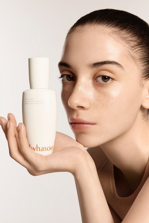 Seorang model memegang FIRST CARE ACTIVATING SERUM VI di satu tangan