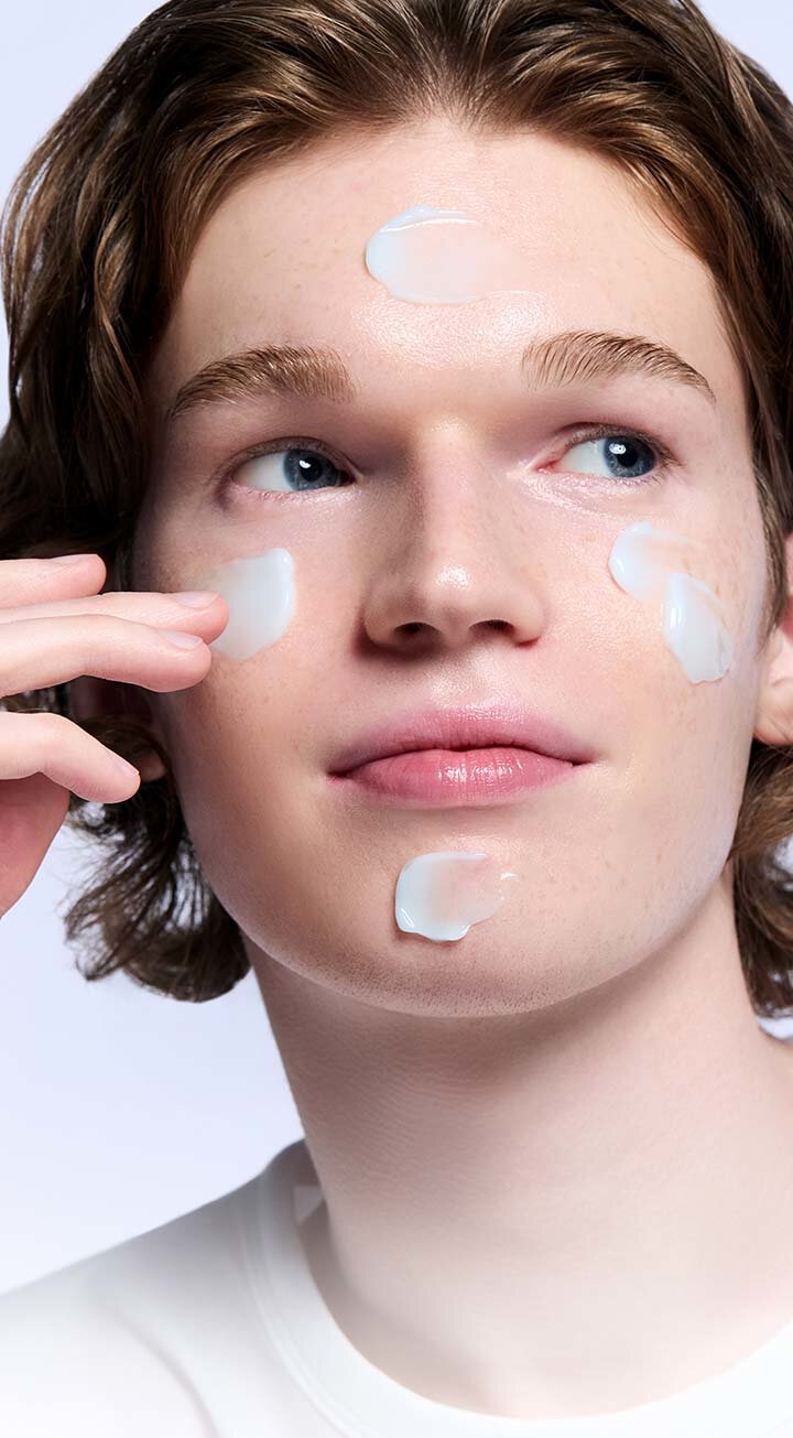 A young man gently applies the LANEIGE Water Sleeping Mask to his face, showcasing the mask's creamy texture and demonstrating its application for a well-rested, radiant complexion.