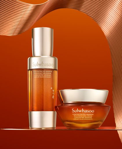 A bottle of Sulwhasoo Concentrated Ginseng Rejuvenating Serum and a jar of Sulwhasoo Concentrated Ginseng Rejuvenating Cream sit together on a reflective surface, showcasing their luxurious amber tones against a rich orange background, promising deeply hydrating and wrinkle-softening benefits.