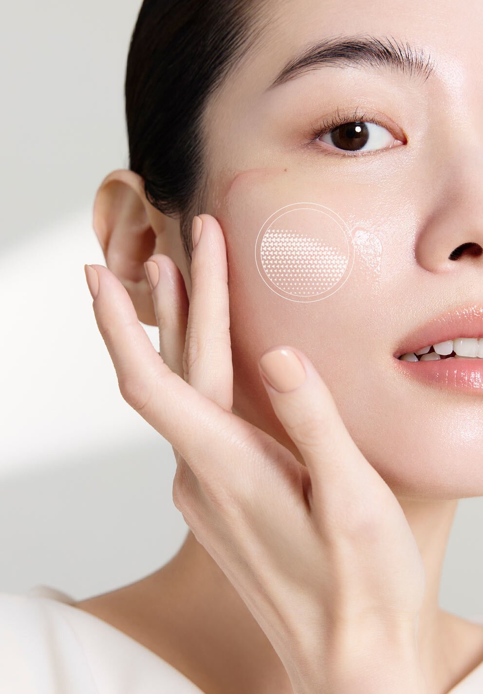 女性以指尖輕柔地將「極致臻秀能量修護安瓶」塗抹於光澤透亮的臉頰上，臉頰上的圓形光效圖案突顯產品深層修護與能量提升的效果。