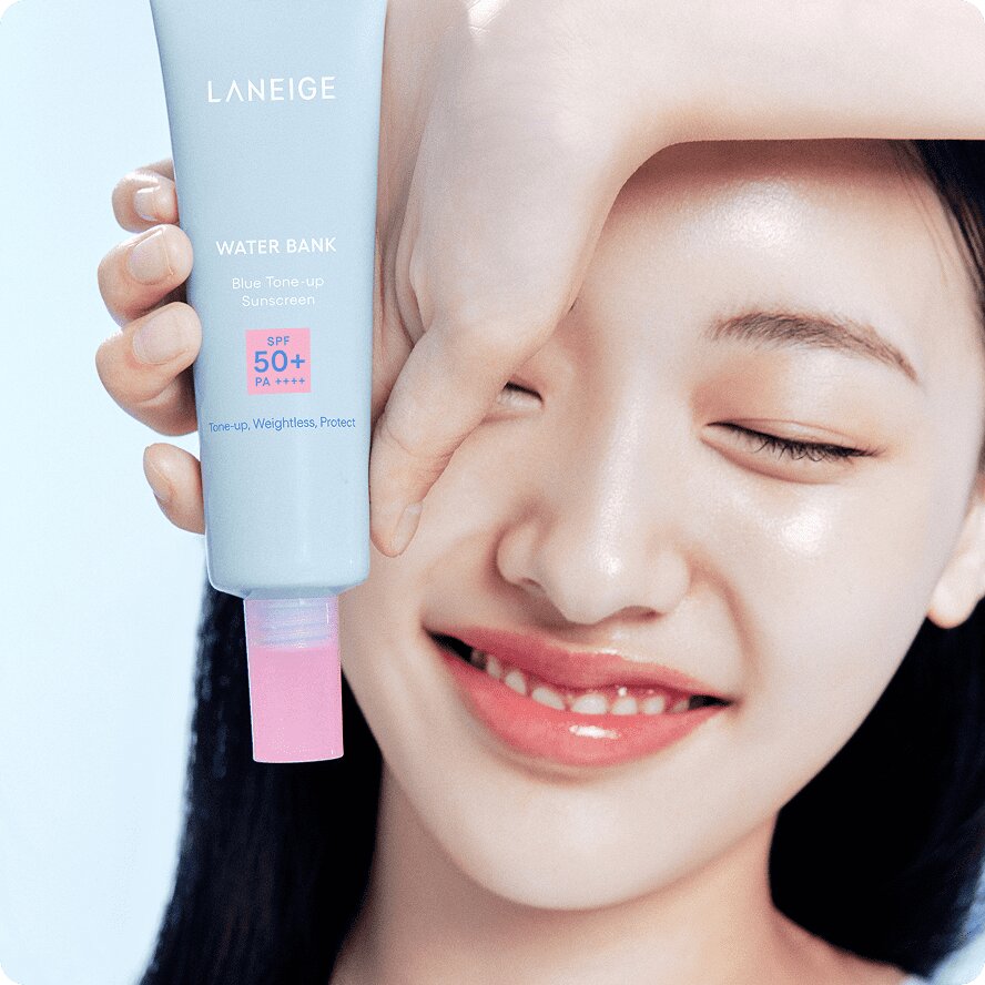 A smiling woman holding WATER BANK Blue Tone-up Sunscreen