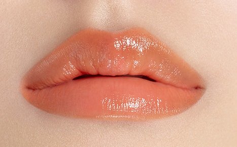 A model with Perfecting Lip Color NO. 520 AMBER applied three times