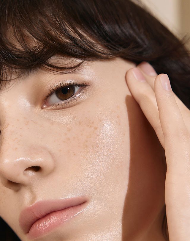 A model who's putting First Care Activating Serum VI on her face.
